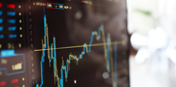 A computer screen showing a fluctuating financial chart with blue and yellow lines, indicating stock market trends