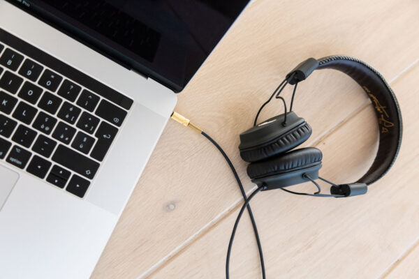 Image of black headphones connected to a grey macbook