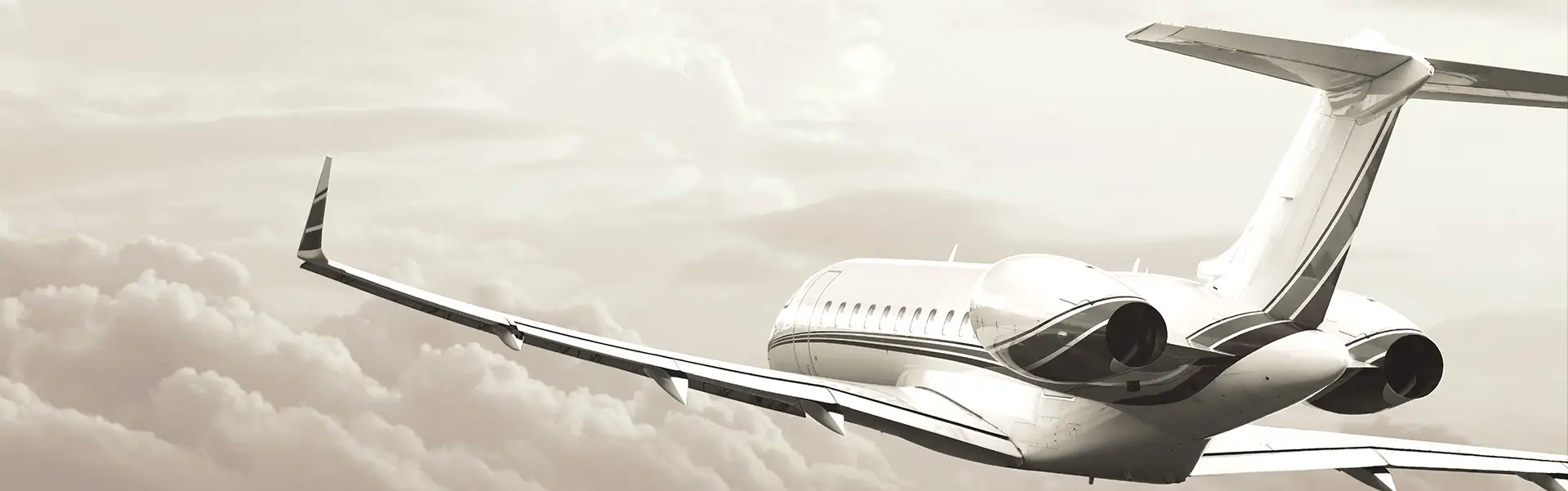 A black and white image of a private jet soaring above the clouds. Gray scale.