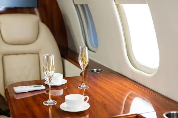 Detail of interior cabin in a private jet, table with two champagne glasses and a coffee cup.