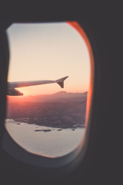 A wing of an airplane from the window seat, with the sunset in the background