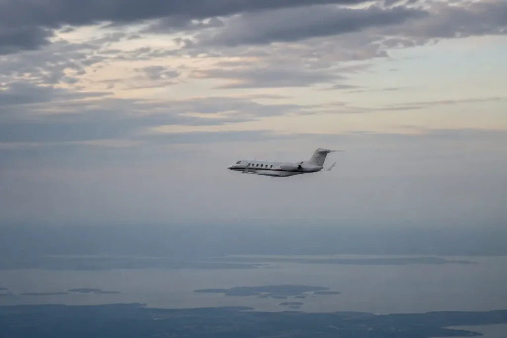 Image of a plane flying over a lake in a cloudy sky.