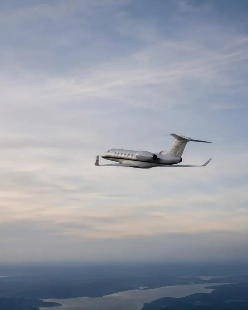 Image of an airplane flying away in a cloudy sky over a lake.