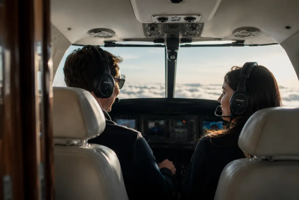 Hero image of a man and a woman sitting in an airplane cockpit in the sky.